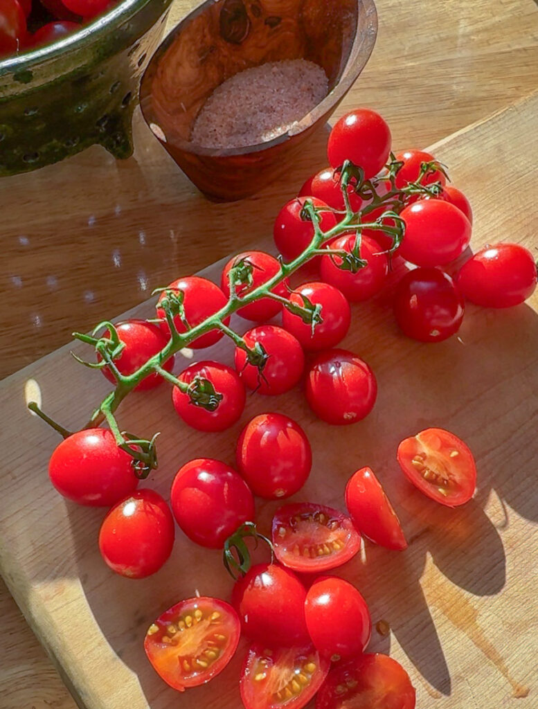 fresh cherry tomatoes on the vine on wooden cutting board