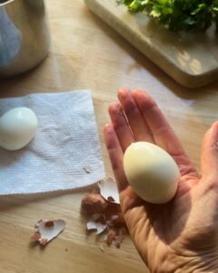 hand holding perfectly peeled hard-boiled egg with cracked shells for easy classic egg salad recipe