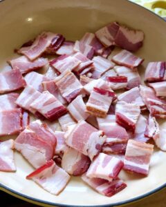 raw chopped bacon pieces in a skillet before cooking for sauteed cabbage recipe