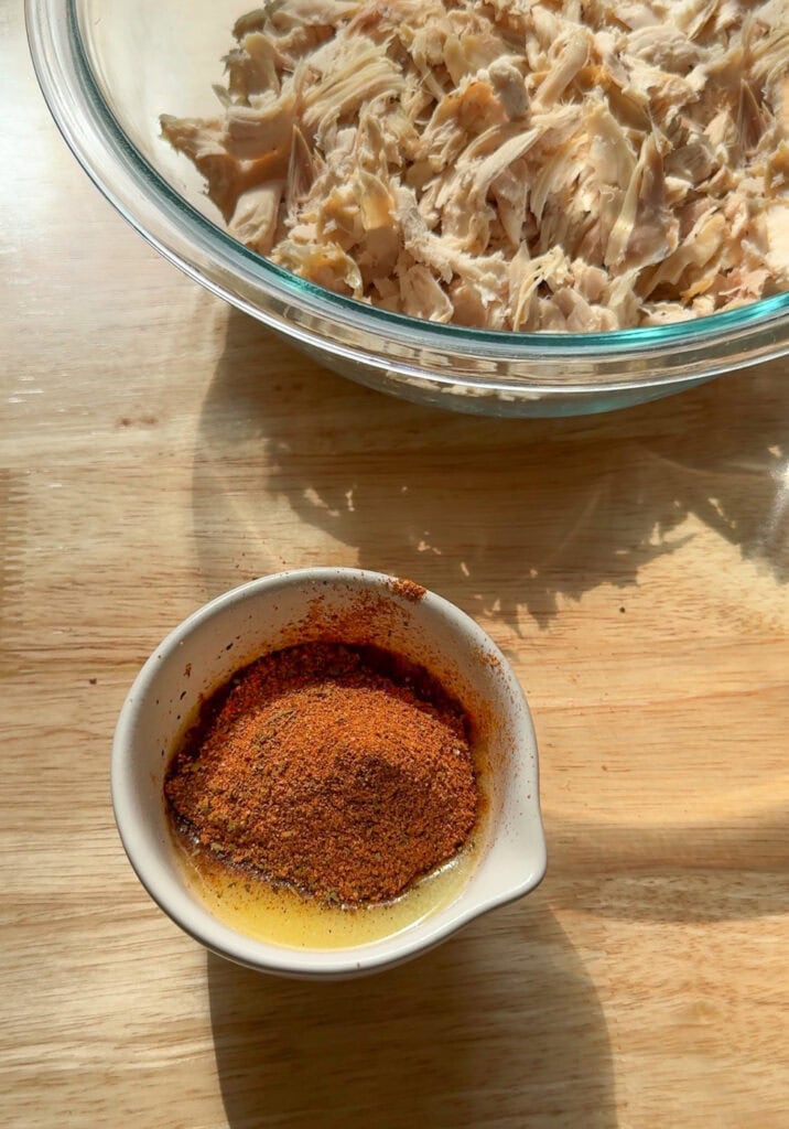 homemade chicken taco seasoning in a small bowl next to shredded chicken