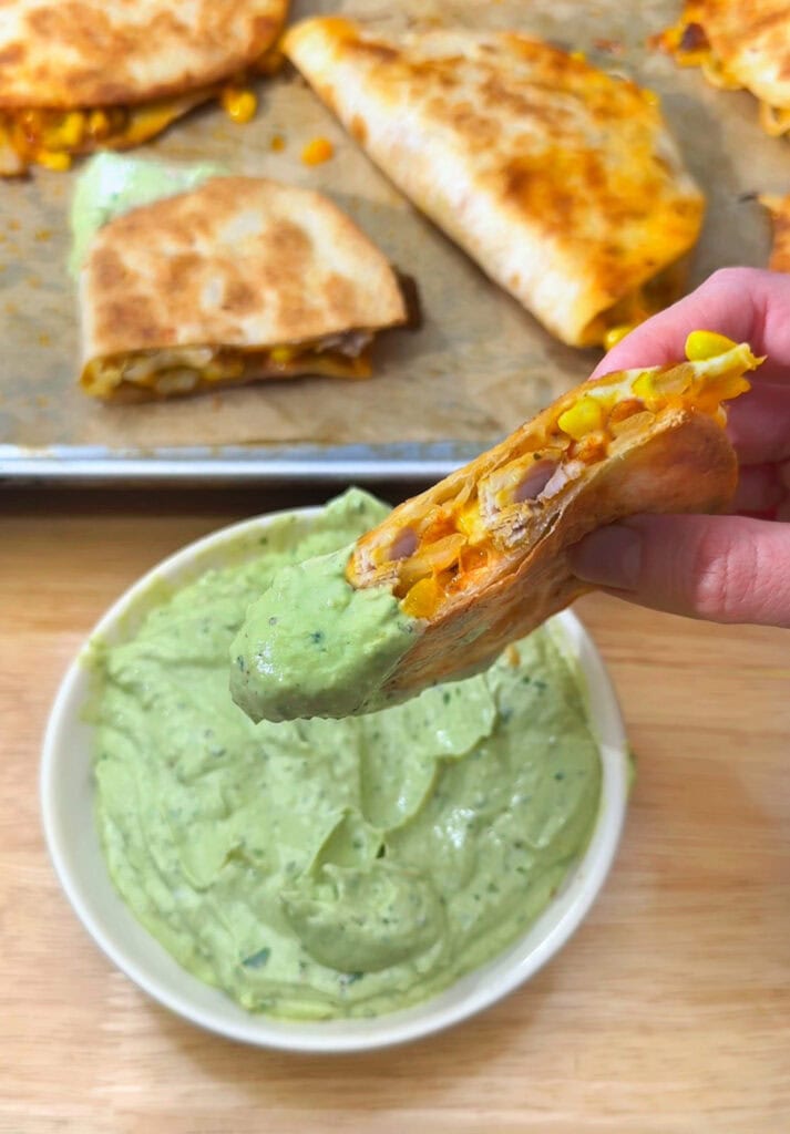 crispy chicken taco dipped into avocado crema
