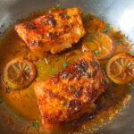 blackened cod fillets in skillet with lemon slices and butter sauce