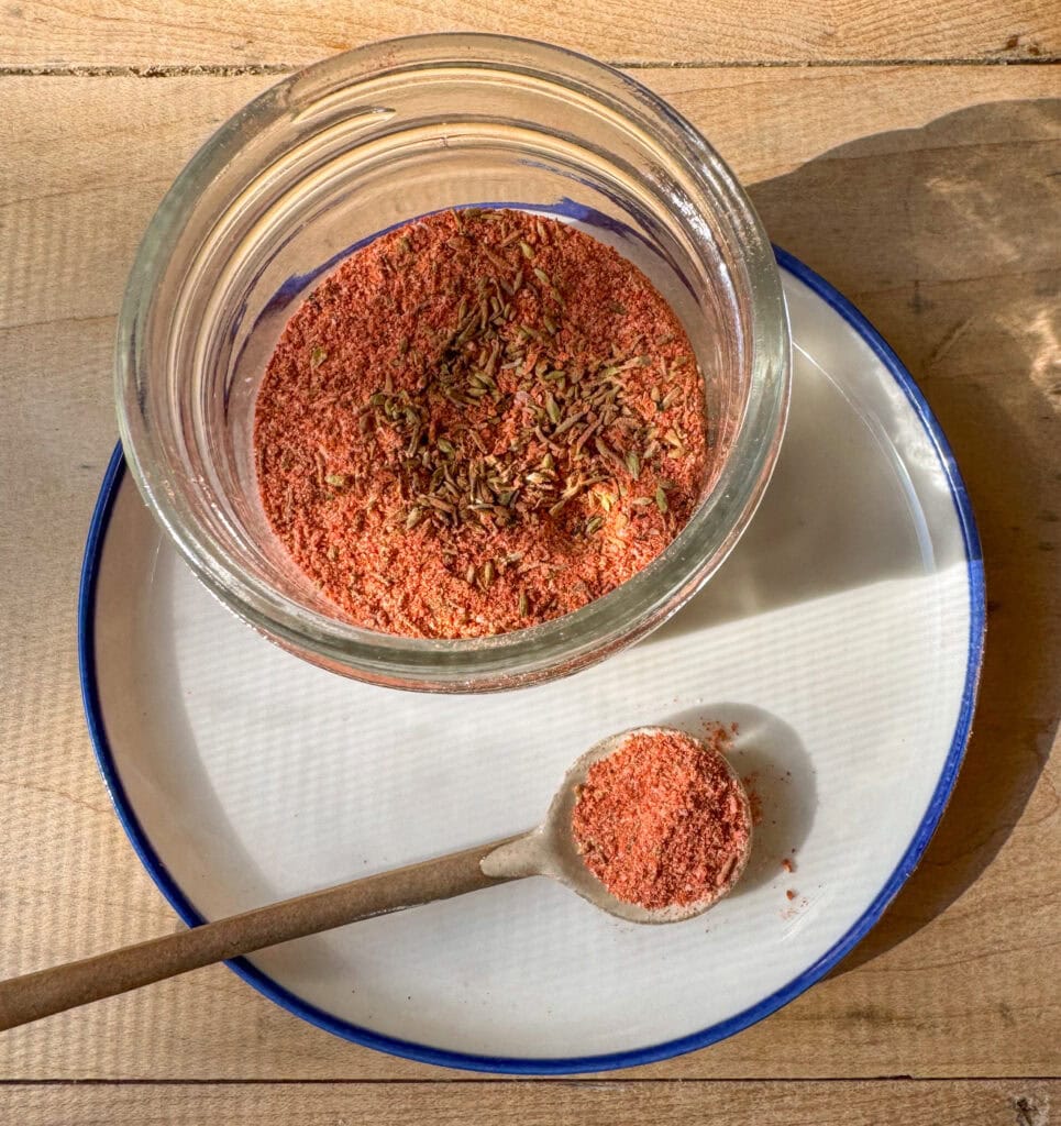homemade blackened seasoning stored in jar with spoon on plate
