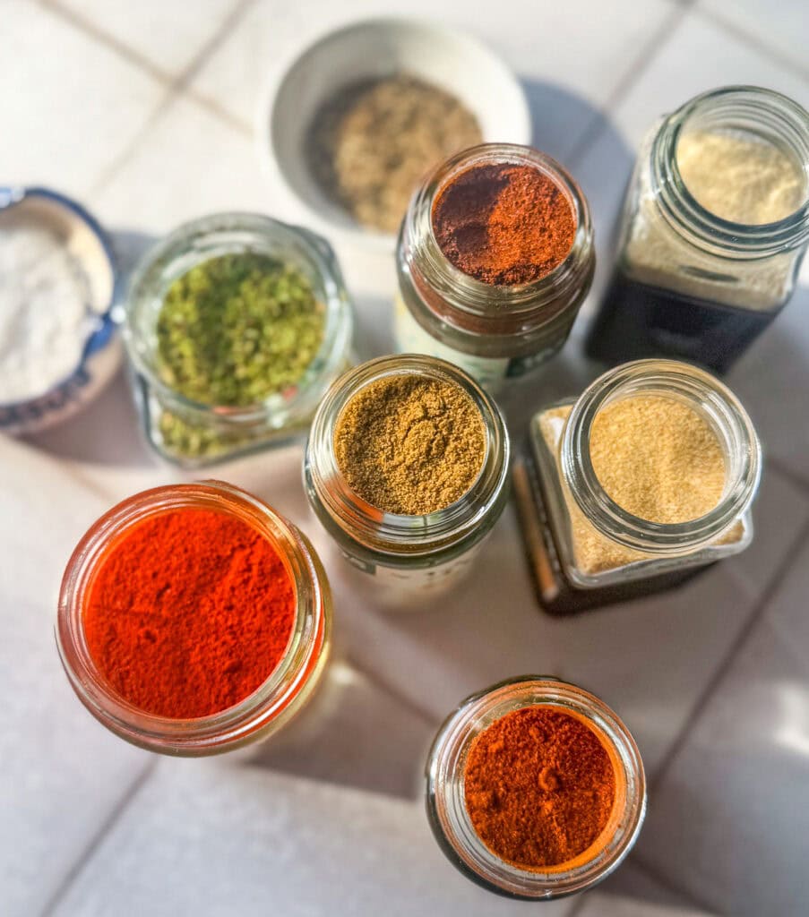 chicken taco seasoning spices in glass jars including paprika cumin garlic powder and chili powder