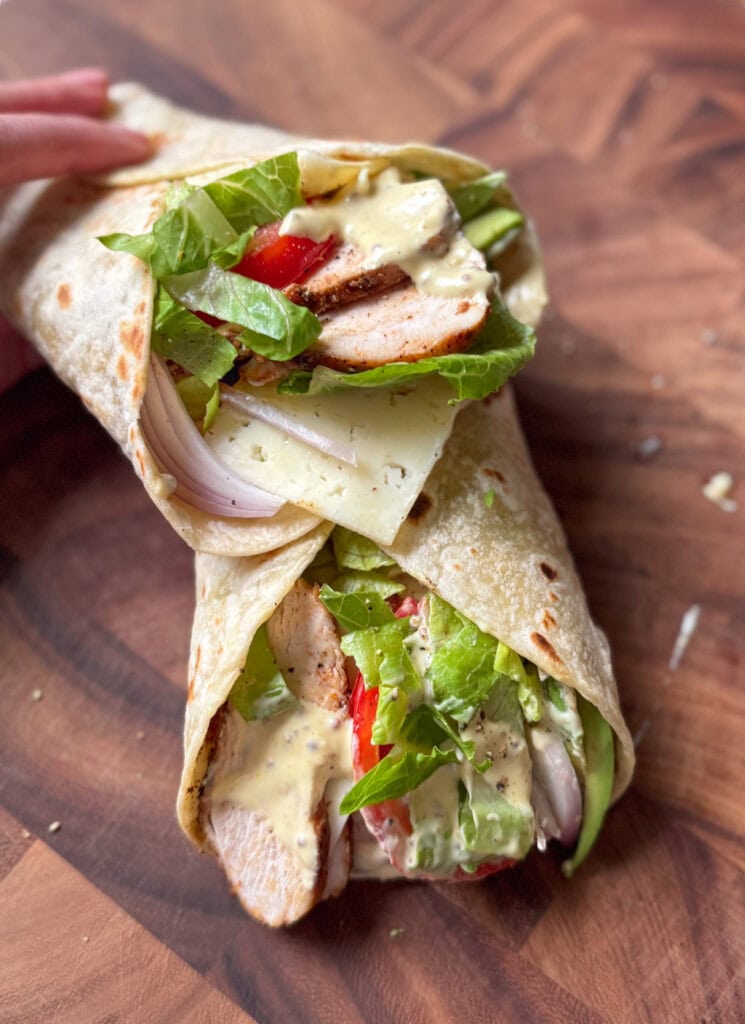 grilled chicken wrap with hot honey mustard sauce, avocado, lettuce, tomato and cheese in tortilla