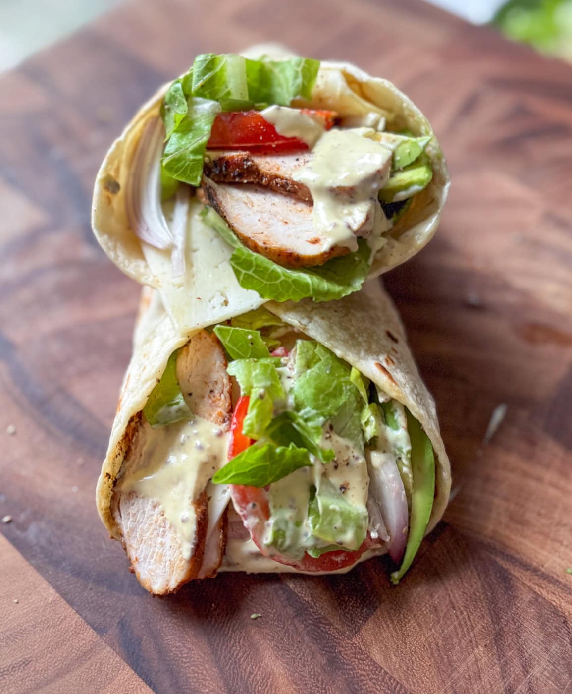 grilled chicken wraps with hot honey mustard sauce, lettuce, tomato, avocado in tortilla
