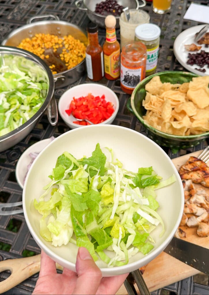omaine lettuce base for southwest chicken salad with grilled chicken, corn, and black beans nearby