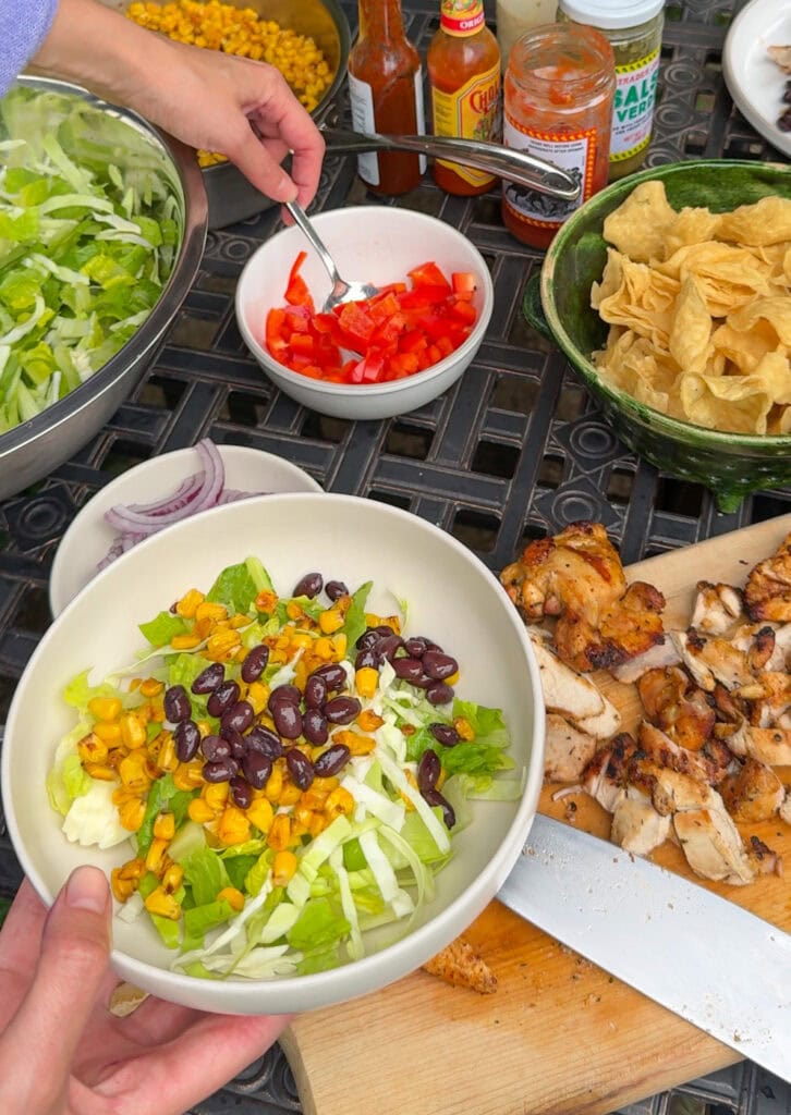 southwest chicken salad with black beans, corn, and grilled chicken being prepared