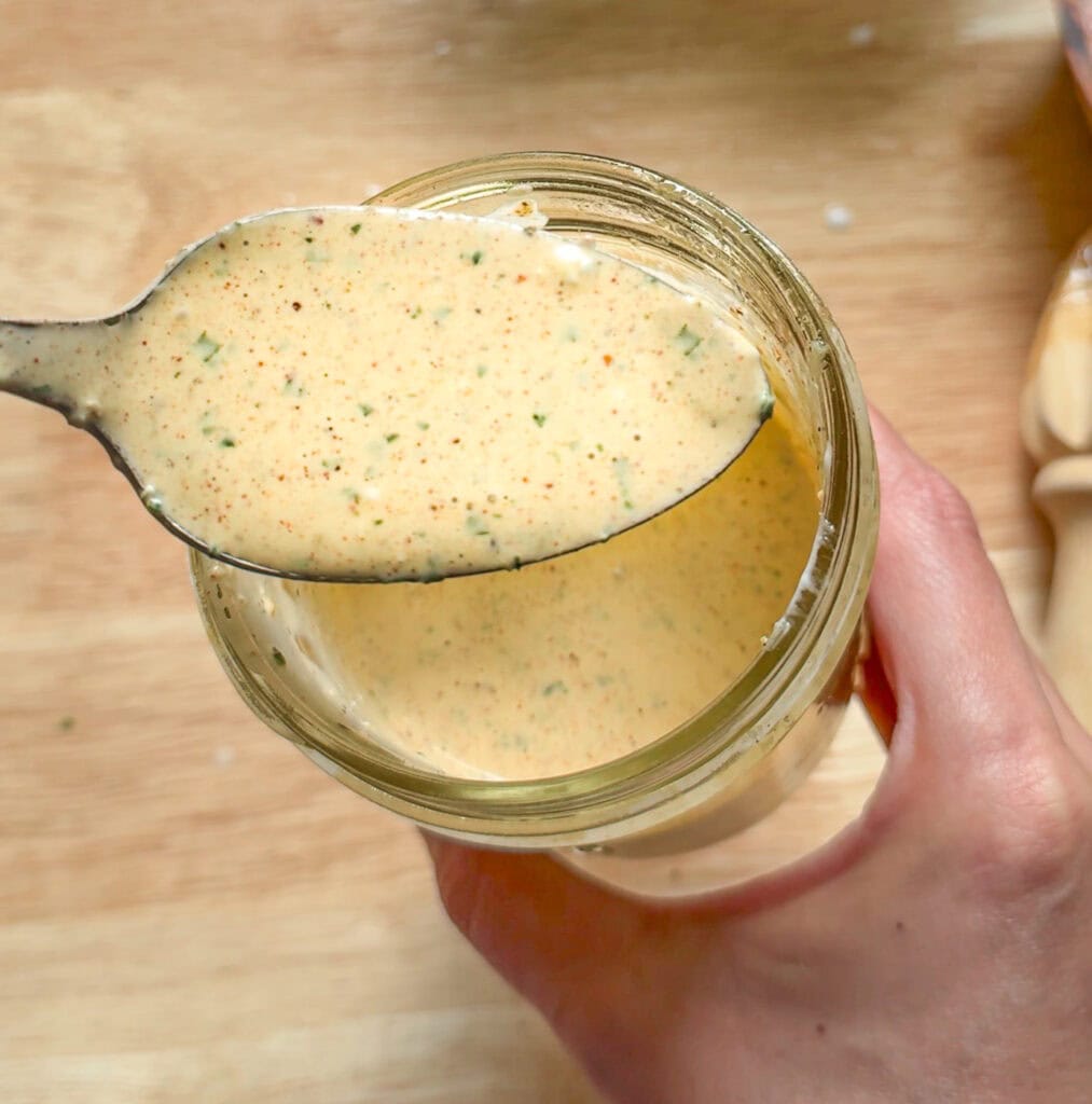 creamy taco salad dressing on a spoon over a jar showing thickness and texture