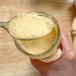 creamy taco salad dressing on a spoon over a jar showing thickness and texture