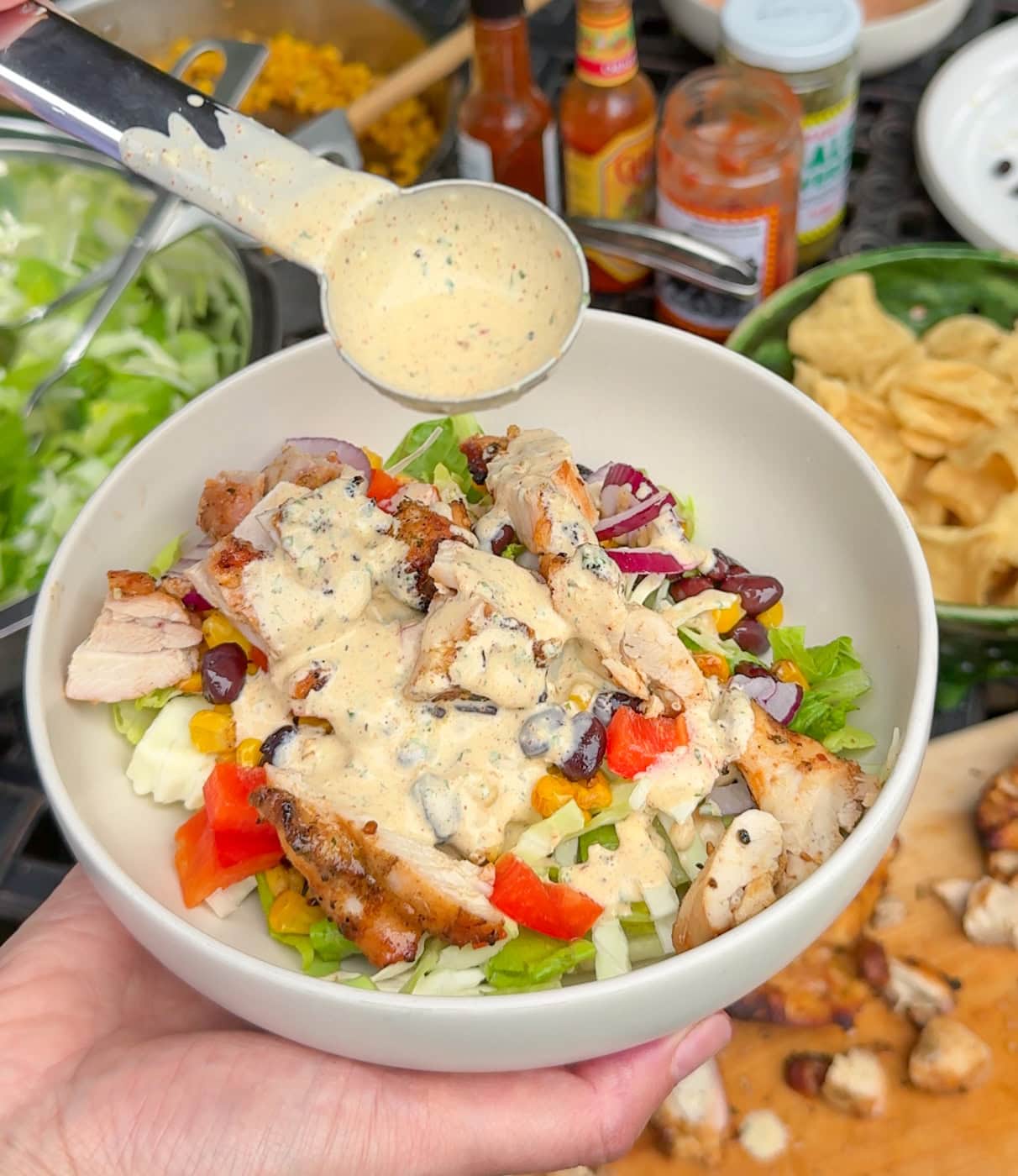 creamy taco salad dressing being poured over grilled chicken southwest salad