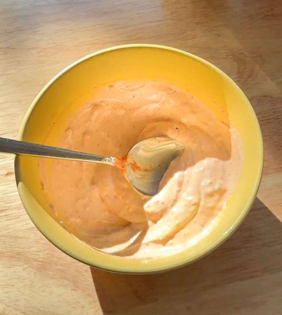 Spicy mayo mixed in a yellow bowl for crispy Asian smash tacos.