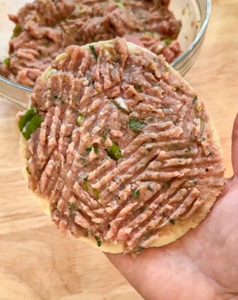 Raw seasoned ground turkey pressed onto a small tortilla for crispy Asian smash tacos.
