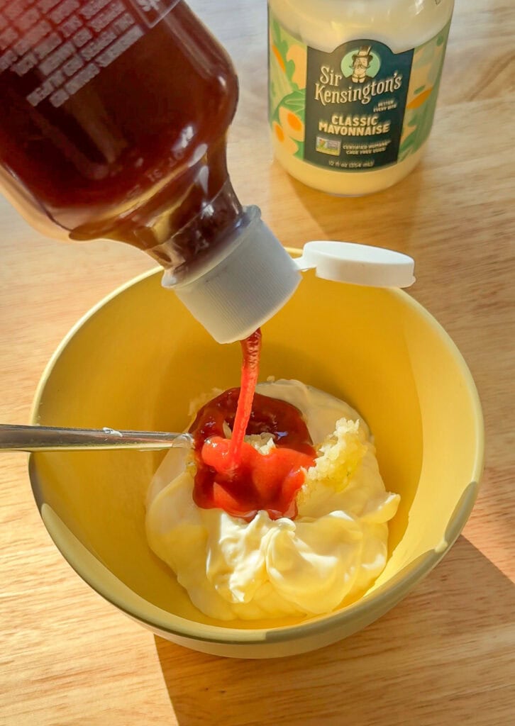 Sriracha being added to mayonnaise for spicy mayo.